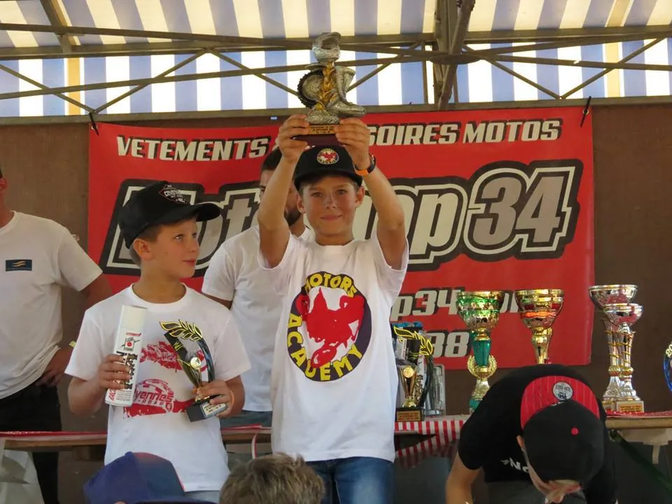 Jeune pilote de l'école brandissant son trophée sur le podium